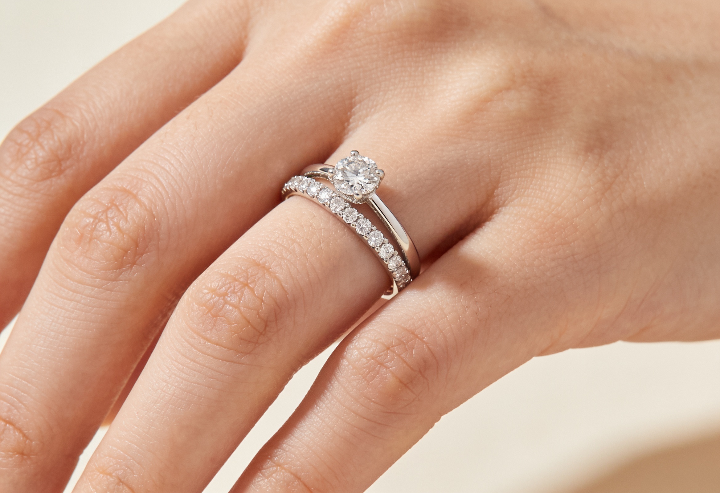 Diamond eternity band stacked with an engagement ring on a hand