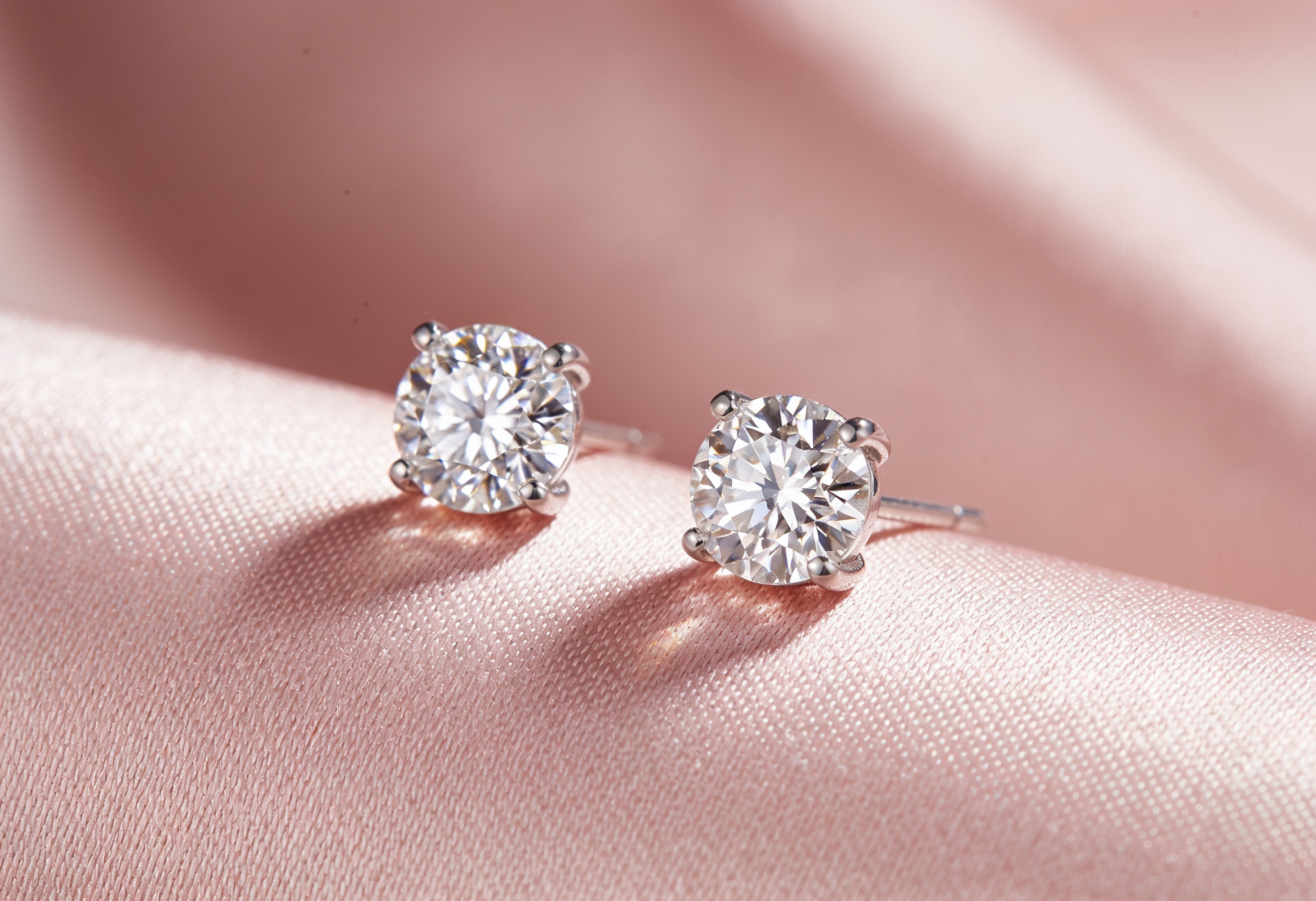 Pair of diamond stud earrings on blush fabric
