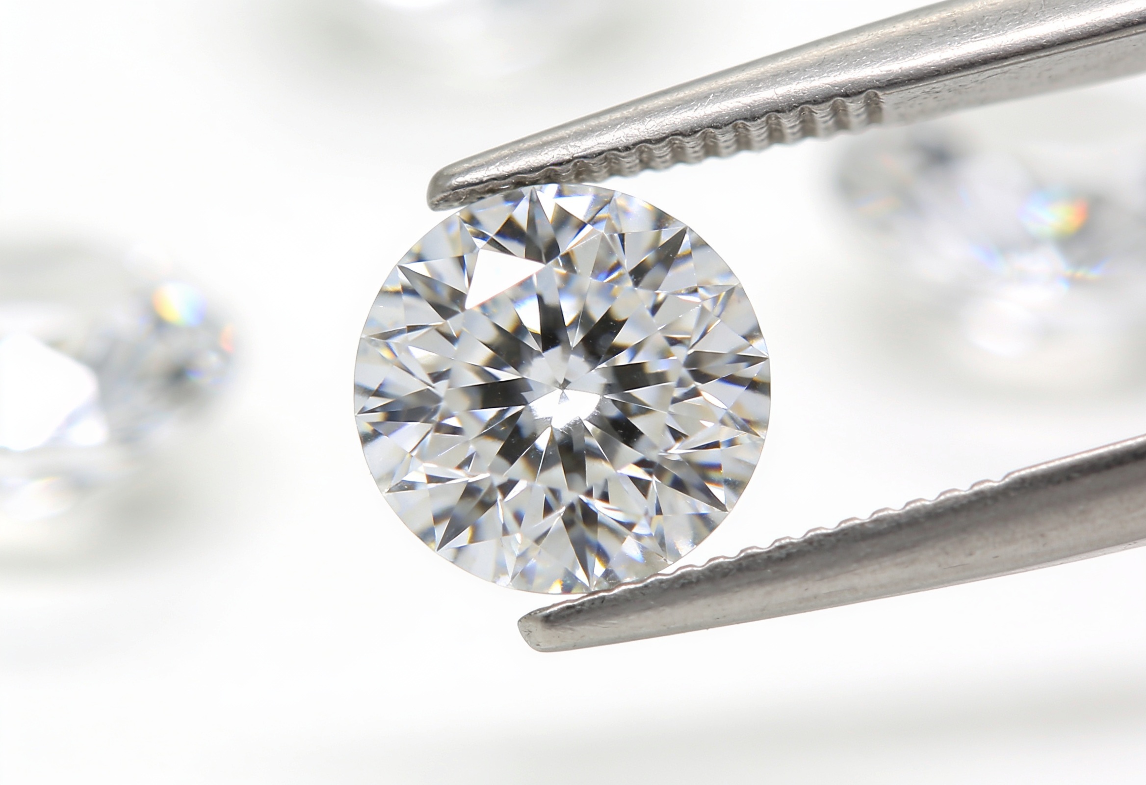 Macro view of a single round brilliant lab grown diamond held in tweezers