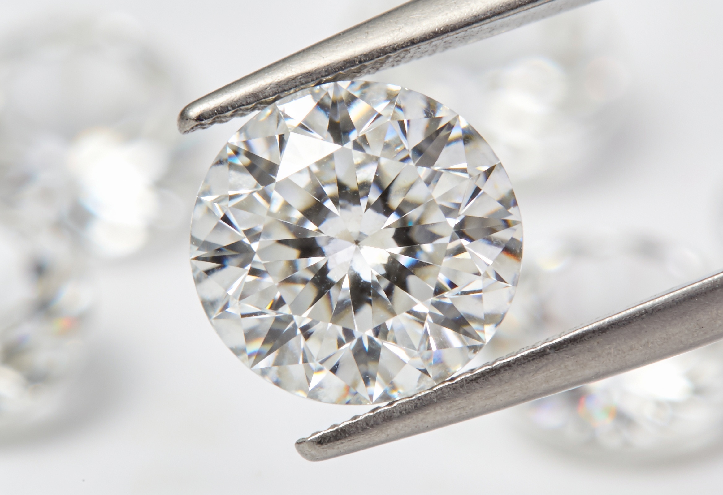 Moissanite vs Lab Grown Diamond 1 Macro view of a round brilliant lab grown diamond held in tweezers