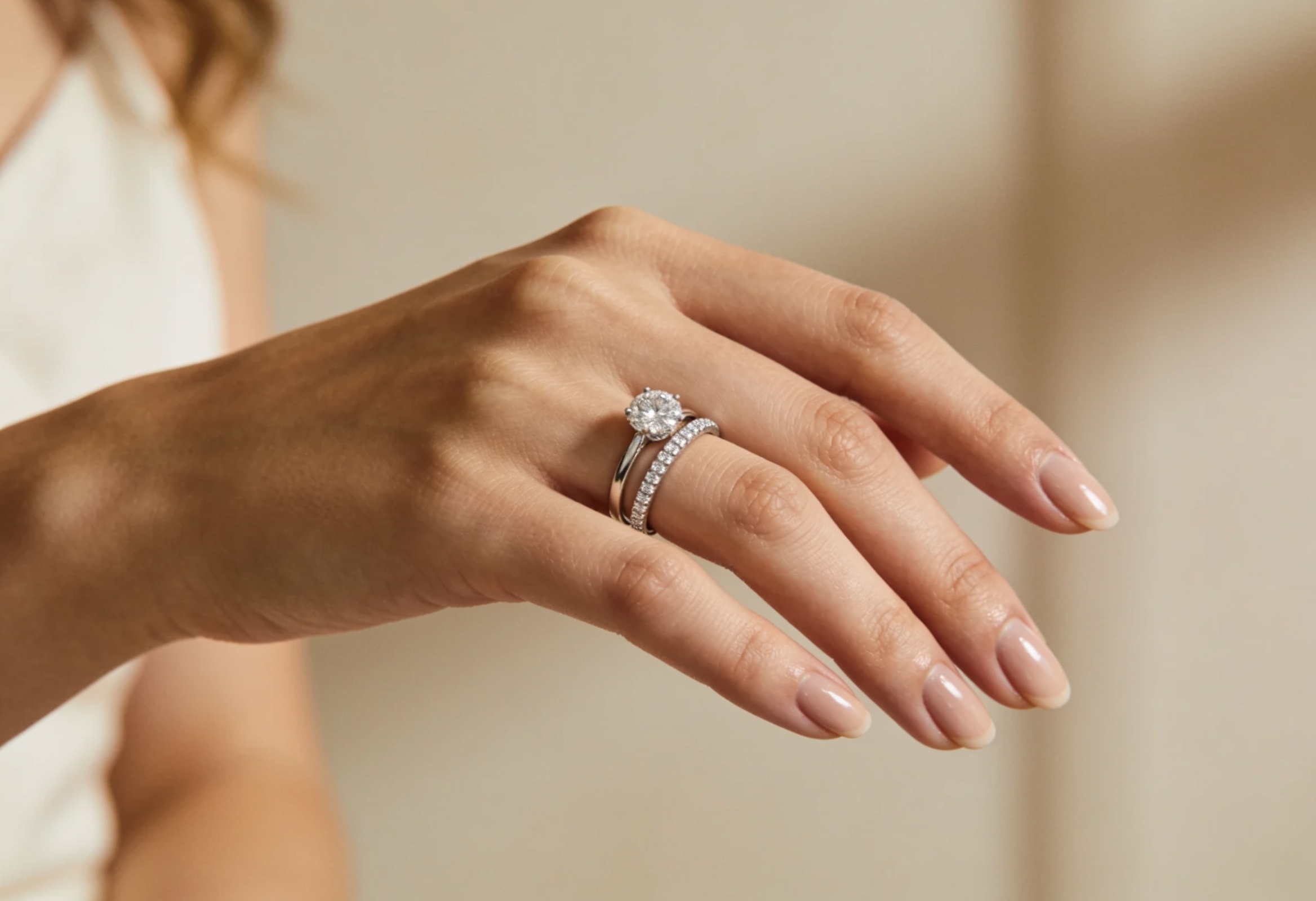 Women's diamond wedding band stacked with a solitaire engagement ring on a hand